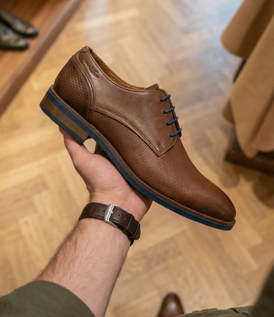 Een bruine leren van Lier-schoen in de hand, in een winkel